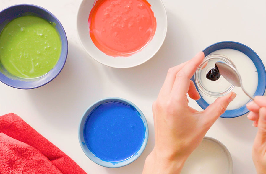 hands mixing food folouring in to bowls of royal icing