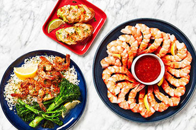 Black tiger shrimp ring, shrimp toasts, and shrimp dinner with rice and broccoli all arranged on marble Surface