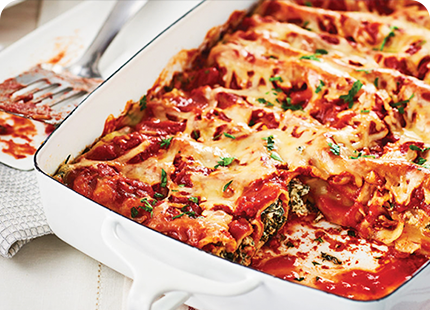 White 9x13 baking dish of Easy Spinach-Ricotta Cannelloni with one serving taken out.