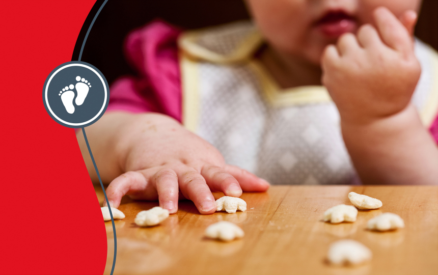 Fingers of a toddler trying first finger foods