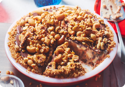 Frozen caramel and nut ice cream pie with slice cut in red pie plate