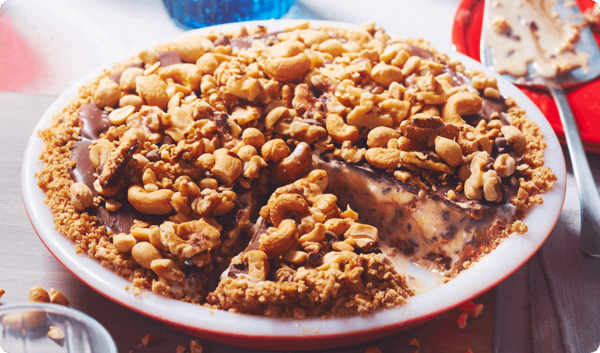 Frozen caramel and nut ice cream pie with slice cut in red pie plate