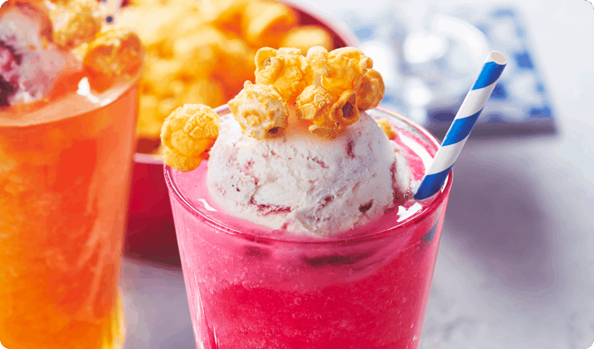 Pink and orange sparkling slushie snack floats in parfait glasses with colourful straws and frozen yogurt scoop on top