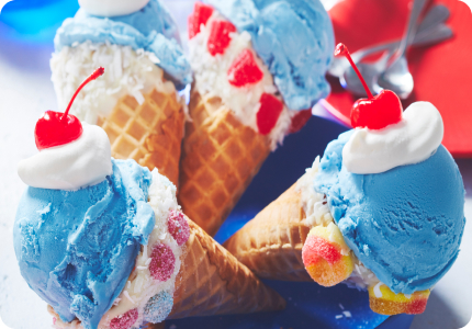 Four chocolate and candy-dipped waffle cones with bubblegum ice cream and a maraschino cherry on top