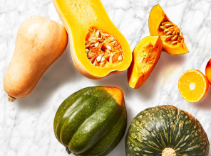 Variety of squashes sliced and whole, on a marble counter top