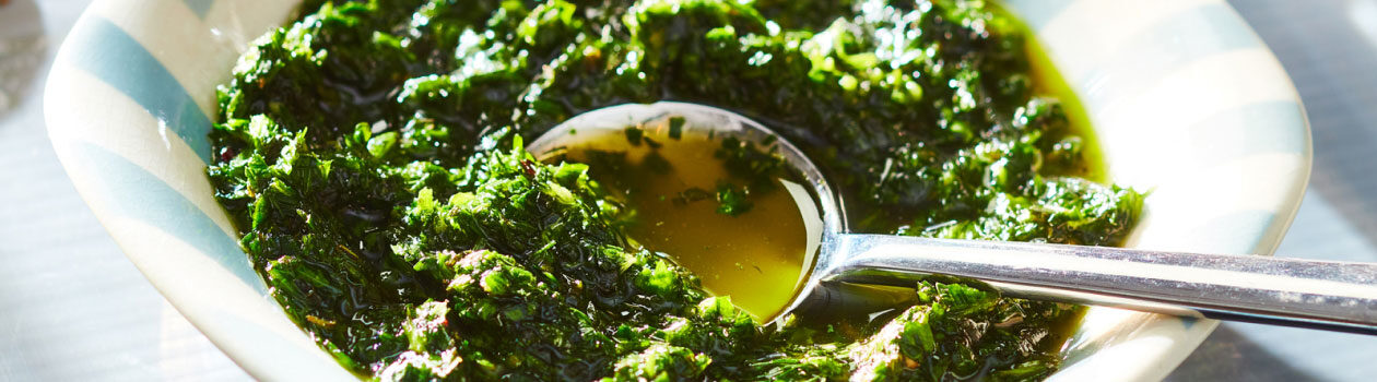 White and blue striped bowl filled with a fresh herb green sauce.