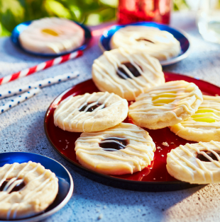 Picnic table with red checkered cloth and red plate of blueberry and lemon thumbprint sugar cookies