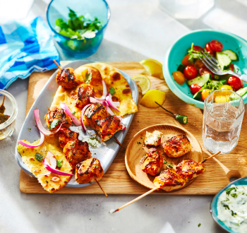 Chicken kabob in a naan wrap with bowl of raita on the side