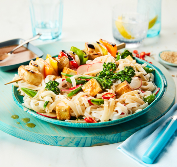 tofu noodle bowl with grilled vegetable skewer on top