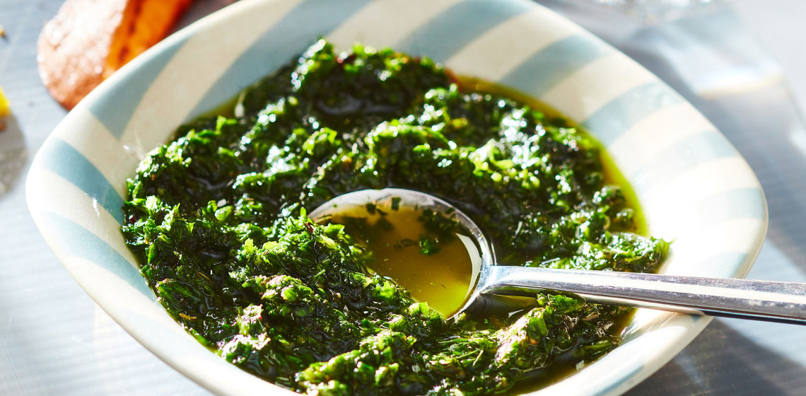 White and blue striped bowl filled with a fresh herb green sauce.