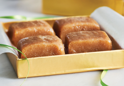 A gold box of gingerbread fudge with a green ribbon.