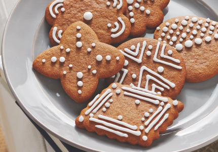 A white plate of gingersnap cookies with royal icing decoration on top.