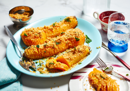 Aqua blue serving platter with three halves of roasted butternut squash, cut in hasselback-style and topped with sage and breadcrumbs