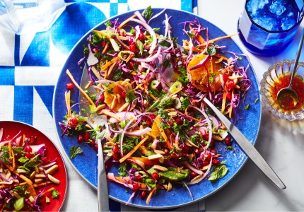 Round blue serving platter of carrot and cabbage lebanese-inspired coleslaw on white and blue placecloth