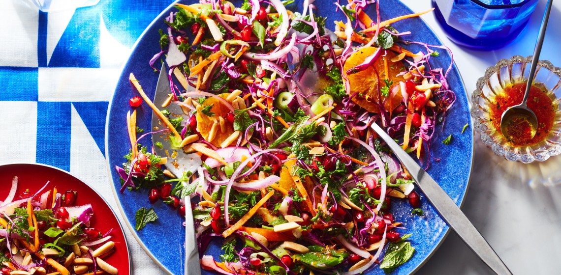 Round blue serving platter of carrot and cabbage lebanese-inspired coleslaw on white and blue placecloth