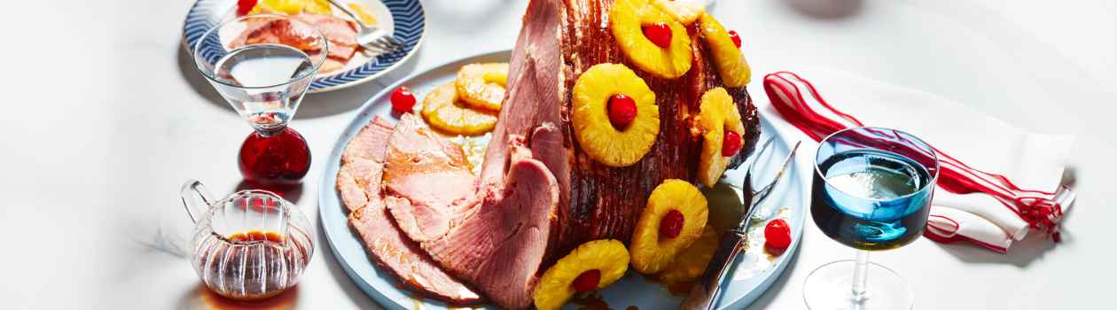 Light blue serving platter with Panache Spiral Sliced Ham studded with pineapple rings and red cherries.