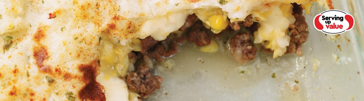 Casserole dish of shepherds pie with scoop out from corner